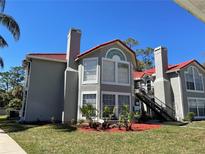 Charming condo building with a red tile roof, beautiful windows, a chimney, and a well-maintained lawn at 935 Northern Dancer Way # 105, Casselberry, FL 32707