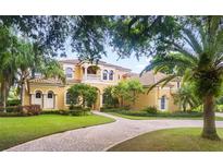 Two-story house with tile roof, manicured lawn, and circular driveway at 1515 Sunset Pointe Pl, Kissimmee, FL 34744