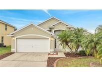 Tan house with white garage door, landscaping, and palm trees at 2318 Andrews Valley Dr, Kissimmee, FL 34758