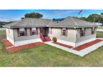 Single-story home with red accents and a spacious yard at 3610 Old Berkley Rd, Auburndale, FL 33823