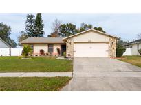 Tan one-story house with pink garage door and stone accents. Landscaped yard at 3618 Willow Lake Ct, St Cloud, FL 34769