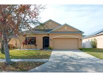 Tan house with a two-car garage and landscaping at 5589 Sycamore Canyon Dr, Kissimmee, FL 34758