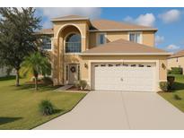 Stunning two-story home featuring a large arched window, a two-car garage, and manicured landscaping at 570 Bristol Cir, Kissimmee, FL 34758