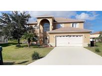 Charming, two-story home showcasing a well-maintained lawn, arched entryway, and attached two-car garage at 570 Bristol Cir, Kissimmee, FL 34758