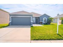 Charming one-story home with a well-manicured lawn, two car garage, and neutral blue paint at 6144 Forest Ridge Way, Winter Haven, FL 33881