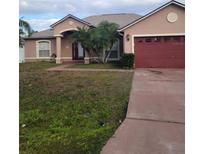 One-story house with red garage door and landscaped lawn at 927 Gloucester Ct, Kissimmee, FL 34758