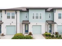 Two-story townhome with light teal siding, two-car garage, and landscaping at 1481 Discovery St, Davenport, FL 33896
