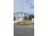 Two-story house with light gray siding, white garage door, and landscaping at 1511 Woodmont Blvd, Kissimmee, FL 34746