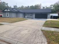 Cozy one-story home featuring a gray exterior, black garage door, and spacious driveway at 4749 Hopespring Dr, Orlando, FL 32829