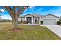 Single-story house with a large tree and well-maintained lawn at 103 Vega Ct, Davenport, FL 33896