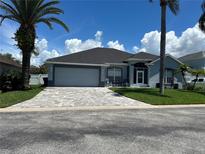 Single-story home with gray exterior, paved driveway, and lush landscaping at 148 Joewood Trl, Davenport, FL 33837