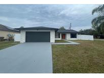 Newly renovated home with gray garage door, white exterior, and landscaped lawn at 202 Cobalt Dr, Kissimmee, FL 34758