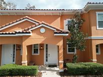 Two-story townhouse with orange exterior, white door, and landscaping at 2717 Coupe St, Kissimmee, FL 34746