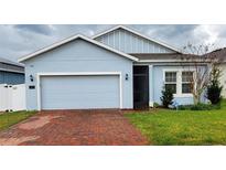 Light blue house with a red brick driveway and a two-car garage at 421 Disa Dr, Davenport, FL 33837