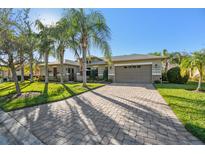 Single-story home with paver driveway, landscaping, and palm trees at 135 Lemon Grove Dr, Poinciana, FL 34759