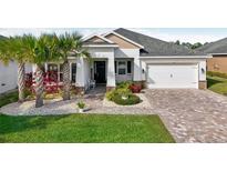 Single-story home with white exterior, landscaping, and paver driveway at 2937 Bella Flore Ter, New Smyrna Beach, FL 32168