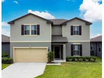 Two-story house with gray siding, neutral accents, and a two-car garage at 446 Citrus Isle Loop, Davenport, FL 33837