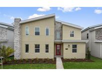 Two-story house with a modern design, red door, and landscaping at 4575 Narrative Ln, Kissimmee, FL 34746