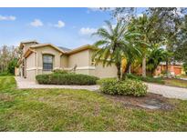 Tan one-story house with a palm tree and landscaped yard at 940 Grand Canal Dr, Poinciana, FL 34759