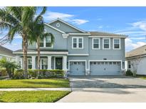 Two-story house with gray siding, three-car garage, and landscaped yard at 8870 Backspin Ln, Champions Gate, FL 33896