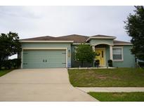 One-story house with a two-car garage and a yellow front door at 1028 Merrimack Blvd, Davenport, FL 33837