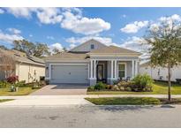 Charming single-story home features a brick driveway, manicured lawn, and a covered front porch with decorative columns at 2051 Flora Pass Pl, Kissimmee, FL 34747