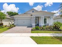 Charming single-story home featuring a two-car garage, covered porch with columns, and a well-manicured front lawn at 2051 Flora Pass Pl, Kissimmee, FL 34747
