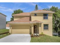 Two-story house with tan exterior, brown roof, and a two-car garage at 3 Peninsular Ave, Haines City, FL 33844