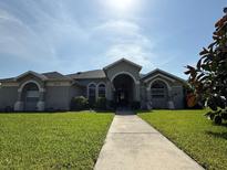 Charming single-story home with manicured lawn, arched entryway, and classic architectural details at 1534 Gants Cir, Kissimmee, FL 34744