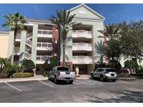 Beautiful condo building featuring multiple balconies, lush landscaping, and ample parking spaces at 1108 Sunset View Cir # 204, Reunion, FL 34747