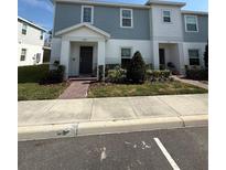 Charming two-story townhome with a beautifully landscaped front yard, brick walkway, and craftsman-style architectural details at 1158 Sand Torch, Davenport, FL 33837