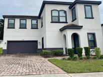 Two-story house with a gray and white exterior, a two-car garage, and landscaping at 122 Macaulays Cv, Haines City, FL 33844