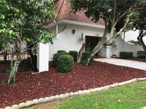 Inviting exterior with mulch bed, trimmed shrubs and trees framing the property and walking path at 4575 S Texas Ave # 207, Orlando, FL 32839