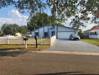 Charming single-Gathering home with a manicured lawn, white picket fence, and a spacious two-car garage at 602 Caddy Dr, Kissimmee, FL 34759