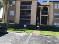Exterior view of condo building with parking and landscaping at 2202 Cascades Blvd # 201, Kissimmee, FL 34741
