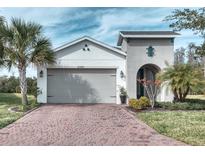 One-story home with gray garage door, landscaping, and brick driveway at 2285 Palm Tree Dr, Kissimmee, FL 34759