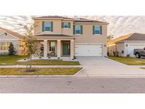Inviting two-story home featuring a two-car garage, manicured lawn, and charming covered front porch with stylish columns at 2778 Sunkissed Dr, St Cloud, FL 34771