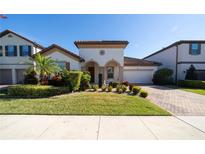 Beautiful two-story home with a well-manicured lawn and brick driveway at 9067 Arbors Edge Trl, Windermere, FL 34786