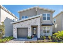 Modern two-story home features a stone facade, gray siding, and a one-car garage at 2797 Bookmark Dr, Kissimmee, FL 34746