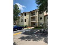 Condo building exterior with parking and landscaping at 3036 Parkway Blvd # 106, Kissimmee, FL 34747