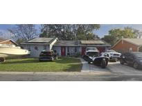 Single story home with solar panels, well-manicured lawn, and multiple vehicles in driveway at 372 La Paz Dr, Kissimmee, FL 34743