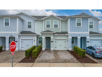 Three-story townhome with two-car garage and landscaped front yard at 4806 Tribute Trl, Kissimmee, FL 34746