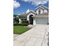 Two-story house with a gray exterior, landscaping, and a two-car garage at 12212 Holly Jane Ct, Orlando, FL 32824