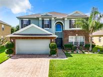Two-story house with brick and siding, a three-car garage, and landscaped yard at 361 Spring Leap Cir, Winter Garden, FL 34787
