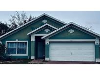Teal house with white garage door and landscaping at 228 Remington Pl, Haines City, FL 33844