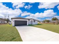 Single-story home with a two-car garage and landscaped lawn at 4690 Sw 139Th Place, Ocala, FL 34473