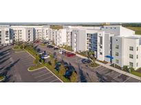 Aerial view of apartment building with parking and surrounding landscape at 4731 Clock Tower Dr # 206, Kissimmee, FL 34746
