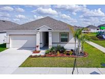White house with gray roof, landscaping, and driveway at 566 Pawnee Ct, Haines City, FL 33844