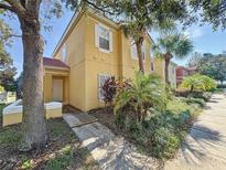Two-story yellow home with walkway and palm trees at 8570 Bay Lilly Loop, Kissimmee, FL 34747