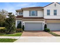 Two-story townhome with gray garage doors and brick driveway at 2935 Rapollo Ln, Apopka, FL 32712
